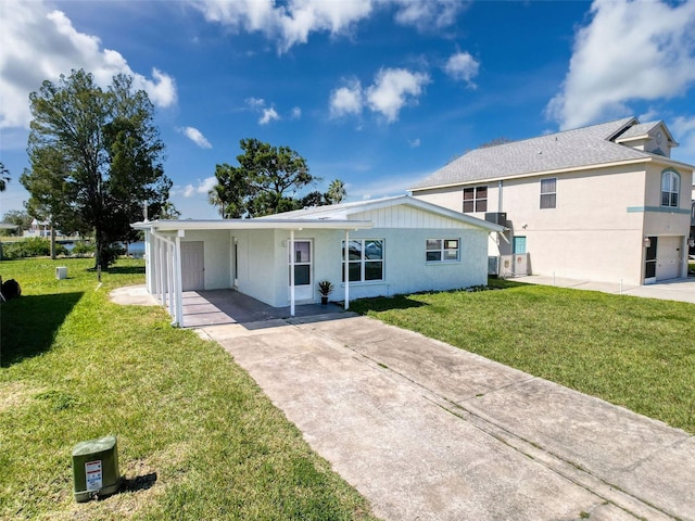 single story home featuring driveway, an attached carport, a front yard, and stucco siding