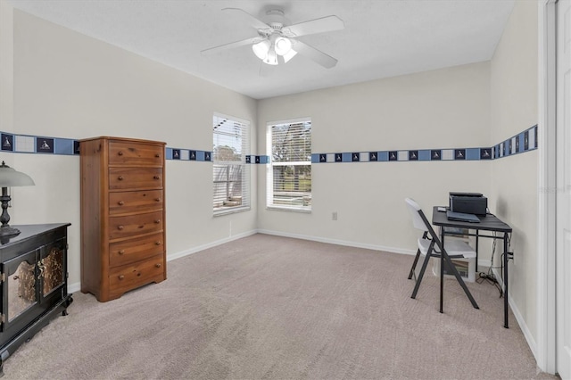 carpeted home office with a ceiling fan and baseboards