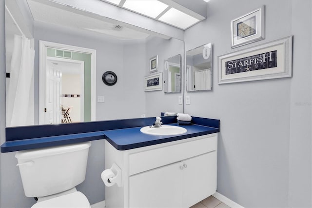 bathroom with toilet, vanity, visible vents, and baseboards