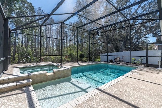 view of swimming pool featuring glass enclosure, a pool with connected hot tub, and a patio