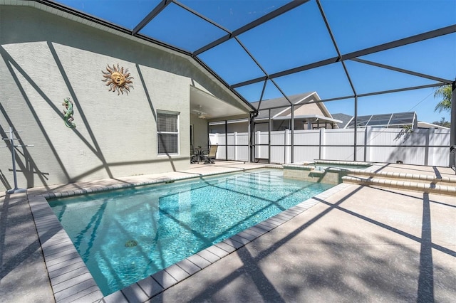 view of swimming pool featuring a patio, glass enclosure, a pool with connected hot tub, and a ceiling fan