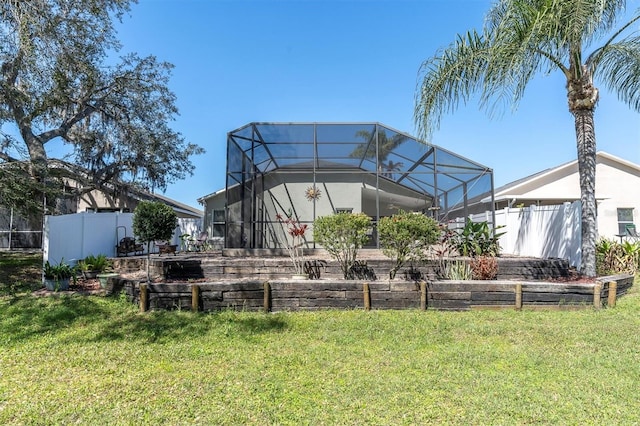 back of house with a lanai, fence, and a yard