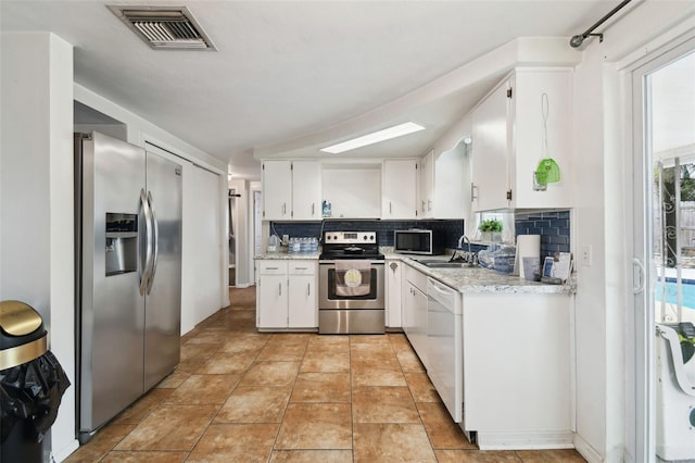 kitchen with stainless steel appliances, a sink, visible vents, white cabinets, and light countertops