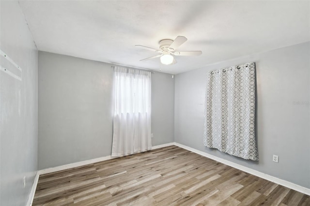 spare room featuring ceiling fan, baseboards, and light wood-style floors