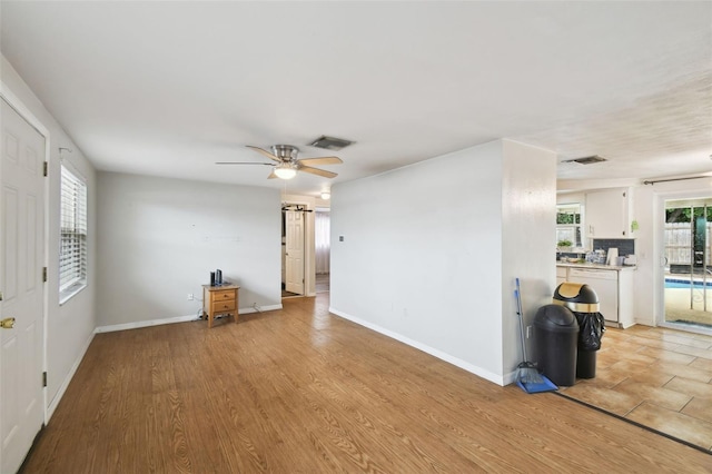 interior space with visible vents, ceiling fan, light wood-style flooring, and baseboards