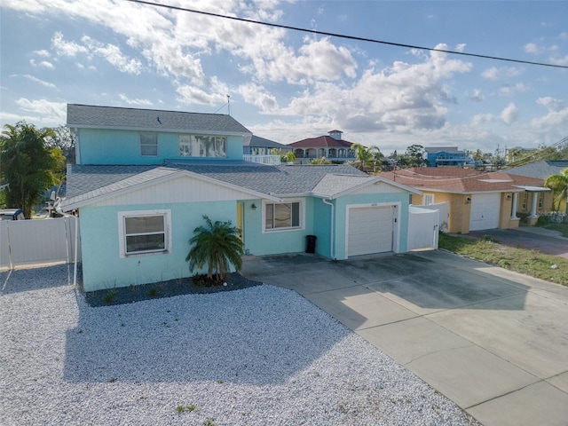 view of front of house with a garage, concrete driveway, a residential view, roof with shingles, and fence