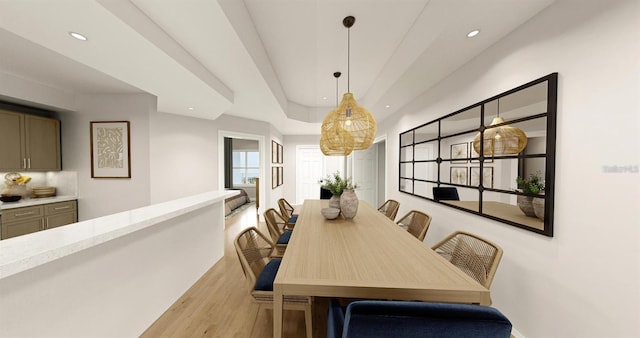 dining space featuring light wood finished floors, a tray ceiling, and recessed lighting