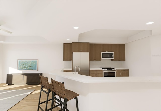kitchen featuring refrigerator, stainless steel range, light countertops, white microwave, and a kitchen bar