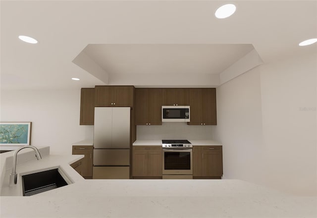 kitchen featuring white microwave, freestanding refrigerator, light countertops, stainless steel range with gas cooktop, and a sink
