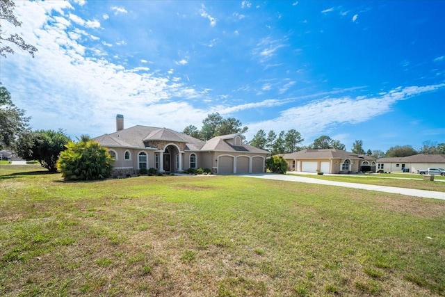 view of front facade with a garage, driveway, a chimney, and a front yard