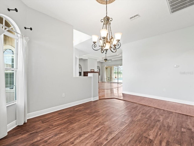 unfurnished dining area featuring baseboards, visible vents, dark wood finished floors, and ceiling fan with notable chandelier