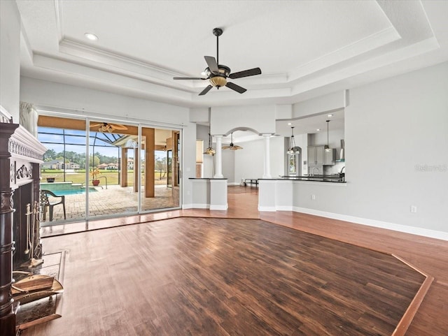 unfurnished living room with ceiling fan, a raised ceiling, and wood finished floors