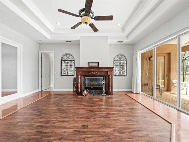 unfurnished living room featuring a raised ceiling, dark wood finished floors, and crown molding