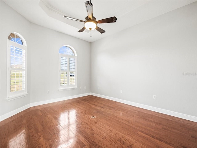 spare room featuring ceiling fan, baseboards, and wood finished floors