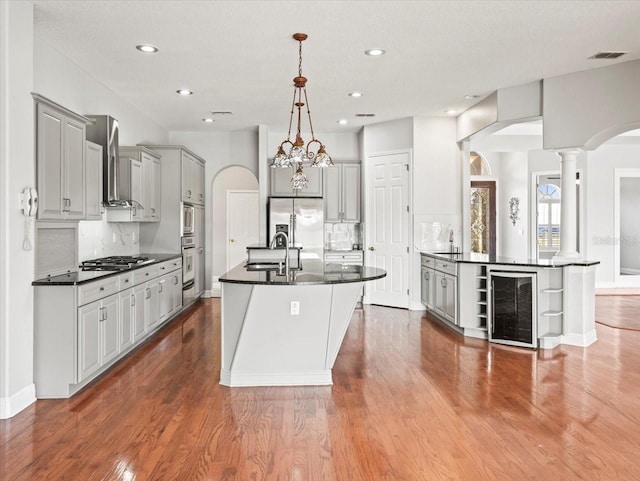 kitchen featuring dark countertops, wine cooler, arched walkways, and gray cabinets