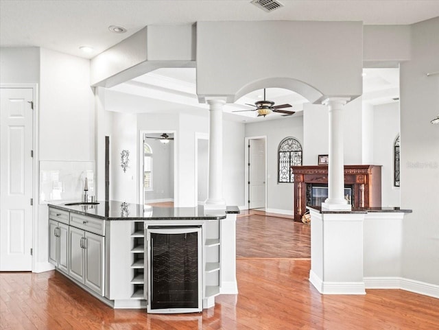 kitchen featuring arched walkways, beverage cooler, decorative columns, and a peninsula