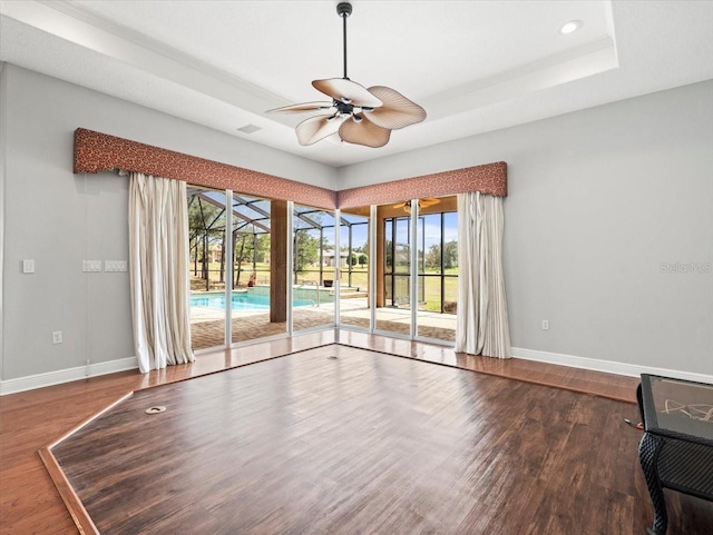 interior space featuring baseboards, a raised ceiling, ceiling fan, dark wood-type flooring, and recessed lighting