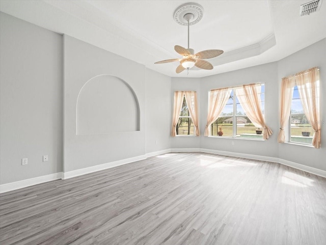 unfurnished room featuring wood finished floors, a ceiling fan, visible vents, baseboards, and a tray ceiling