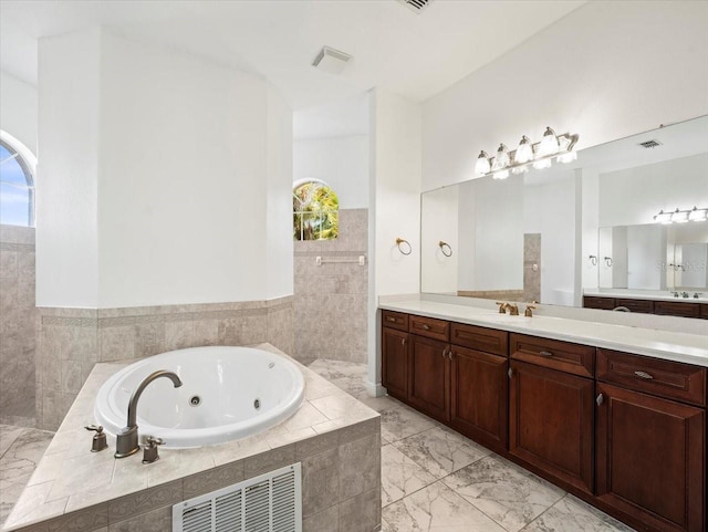 full bathroom featuring marble finish floor, a tub with jets, visible vents, and vanity