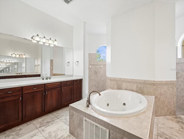 bathroom featuring marble finish floor, visible vents, vanity, and a tub with jets