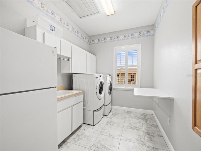 washroom with cabinet space, baseboards, washing machine and clothes dryer, marble finish floor, and a sink