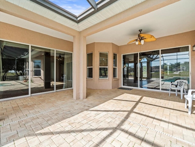 view of patio with glass enclosure and a ceiling fan