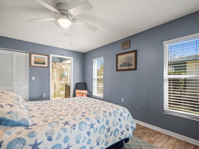 bedroom featuring baseboards, connected bathroom, wood finished floors, a textured ceiling, and a closet