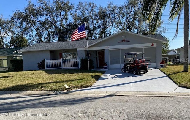 ranch-style home with a garage, driveway, a front yard, and stucco siding