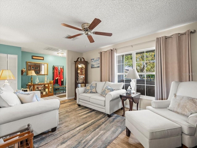 living room with visible vents, ceiling fan, a textured ceiling, and wood finished floors