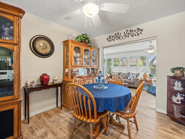 dining room with light wood-style floors, ceiling fan, baseboards, and a textured ceiling