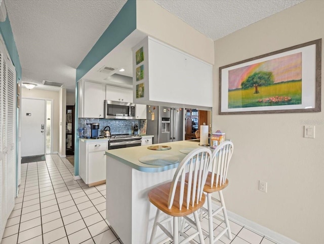 kitchen with light tile patterned floors, stainless steel appliances, tasteful backsplash, and white cabinets