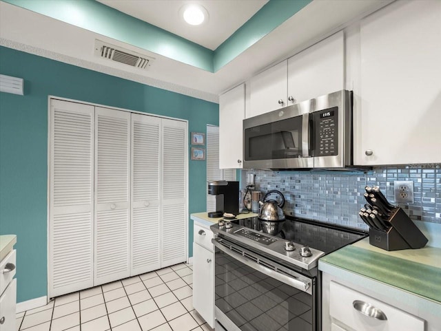 kitchen featuring stainless steel appliances, visible vents, white cabinetry, light countertops, and backsplash