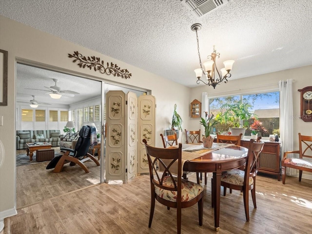 dining space with a chandelier, a textured ceiling, wood finished floors, and visible vents