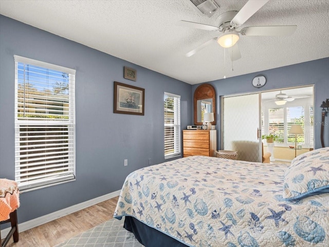 bedroom featuring multiple windows, light wood-type flooring, visible vents, and baseboards