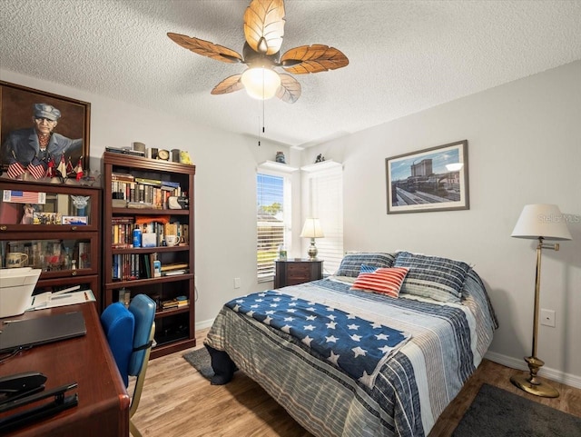 bedroom with light wood-style floors, ceiling fan, a textured ceiling, and baseboards