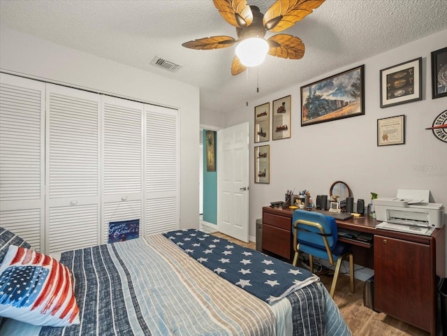 bedroom with visible vents, a ceiling fan, wood finished floors, a textured ceiling, and a closet