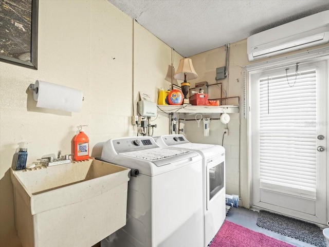 laundry room featuring washer and clothes dryer, a wall mounted AC, a sink, a textured ceiling, and laundry area