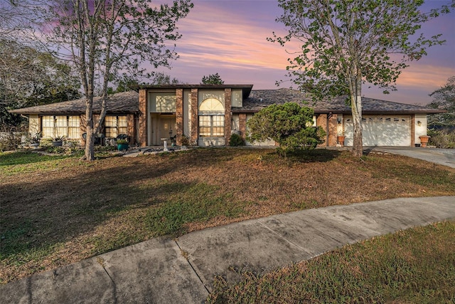 mid-century inspired home featuring an attached garage, a yard, and concrete driveway