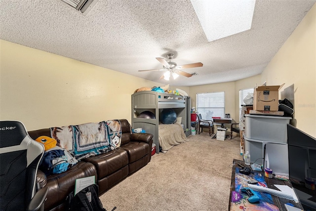 interior space with ceiling fan, a textured ceiling, a skylight, carpet flooring, and visible vents