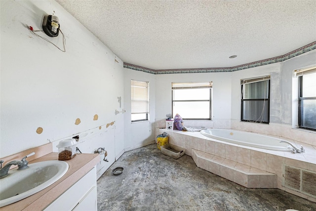 bathroom with visible vents, a textured ceiling, vanity, concrete flooring, and a bath