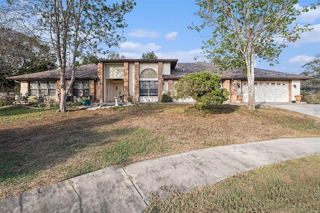 view of front facade with a garage, a front yard, concrete driveway, and brick siding