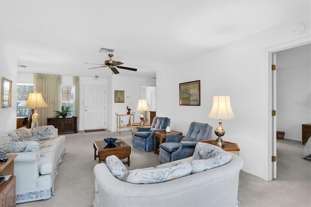 living room featuring a textured ceiling, visible vents, a ceiling fan, and light colored carpet