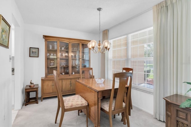 dining space featuring light carpet, baseboards, a chandelier, and a textured ceiling