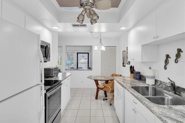 kitchen with appliances with stainless steel finishes, white cabinets, and a tray ceiling