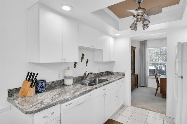 kitchen featuring a tray ceiling, white appliances, white cabinets, and a sink