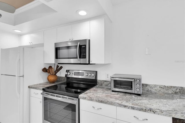 kitchen with appliances with stainless steel finishes, a toaster, white cabinetry, and light stone counters