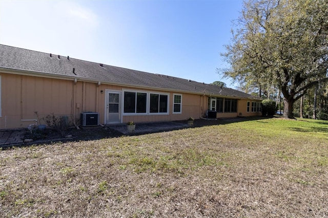 rear view of house with central AC unit, a lawn, and board and batten siding