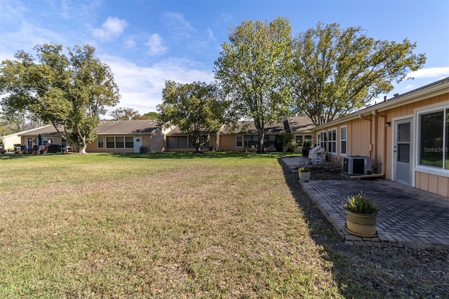 view of yard with a residential view, central AC, and a patio