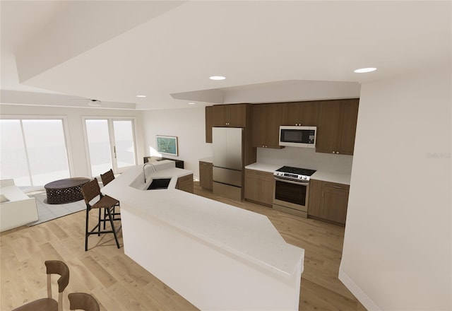 kitchen with light wood-style floors, a center island, refrigerator, light countertops, and stainless steel range oven