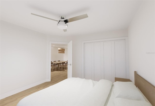 bedroom with light wood-style floors, a closet, ceiling fan, and baseboards